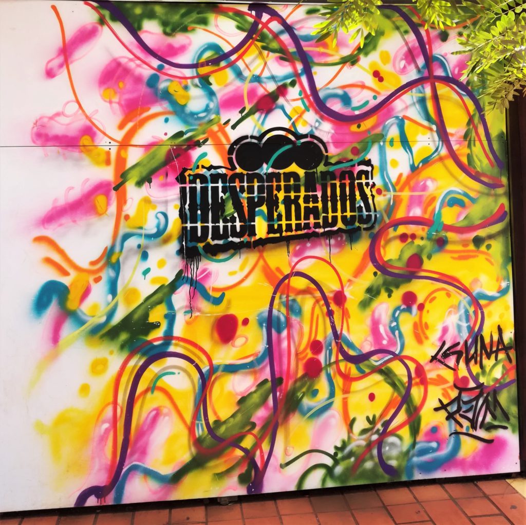 Oeuvre street art faisant la publicité pour la bière Desperados avec un fond coloré