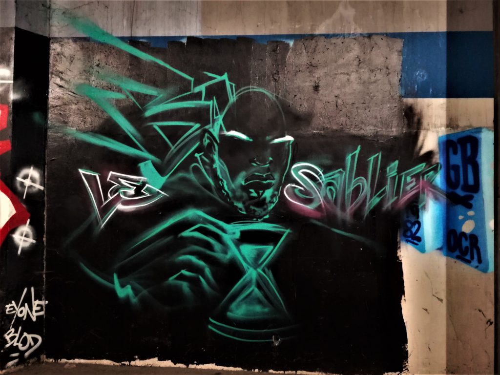 Graffiti représentant un homme vert sur fond noir possédant un sablier