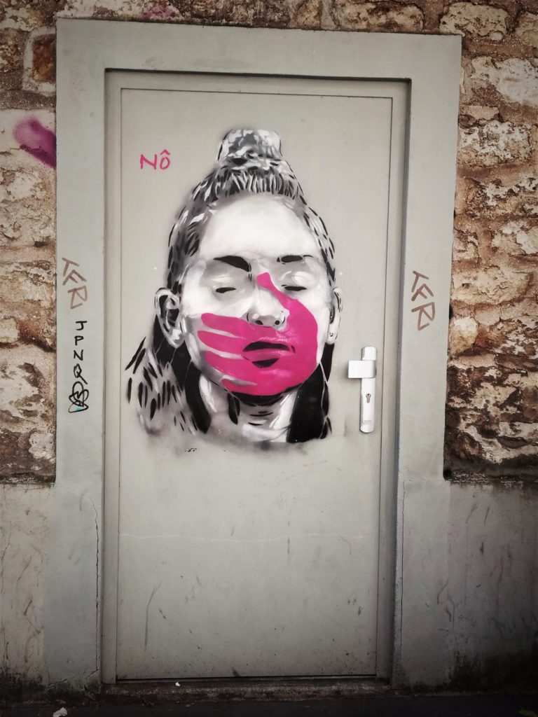 Graffiti représentant une jeune fille en noir & blanc avec une main rose sur la bouche