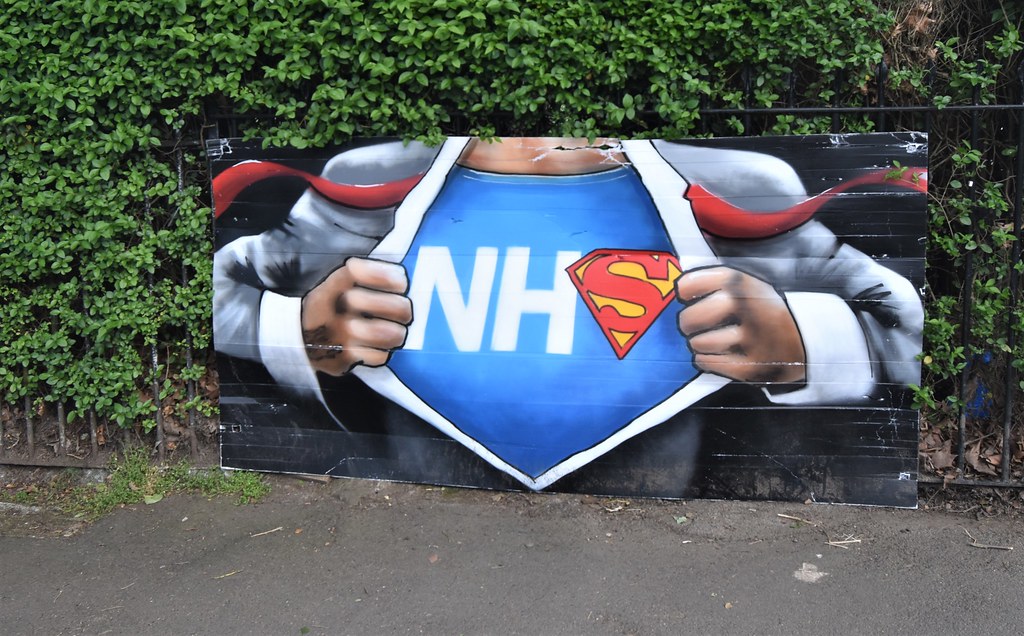 Photo d'un homme ouvrant sa chemise et dévoilant le terme NHS (avec le S de Superman)