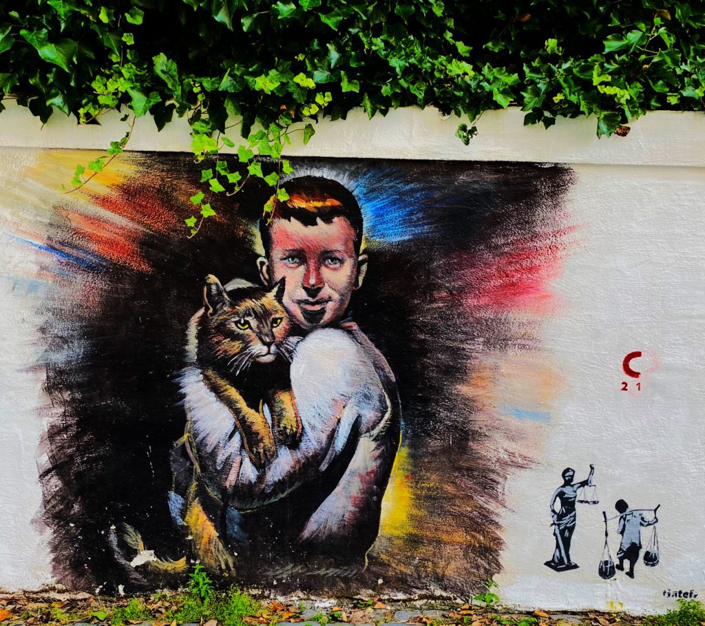 Street art représentant un enfant portant un chat dans ses bras